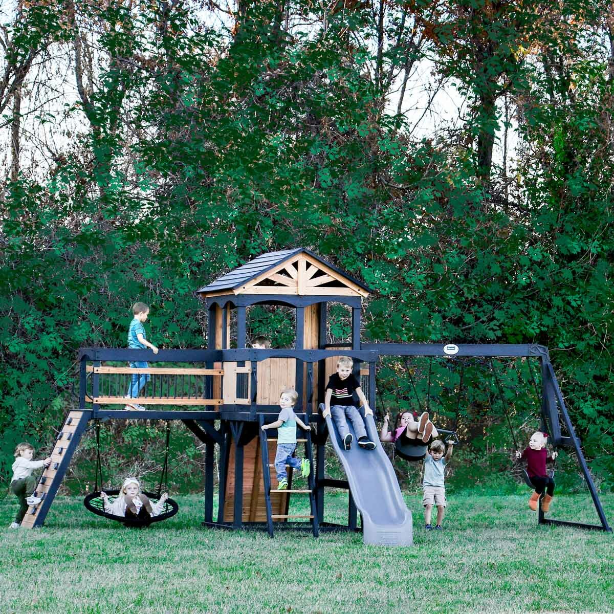 Lifestyle image of children playing on the Backyard Discovery Timber Crossing Wooden Playcentre and Swing Set Lifestyle image of children playing on the Backyard Discovery Timber Crossing Wooden Playcentre and Swing Set