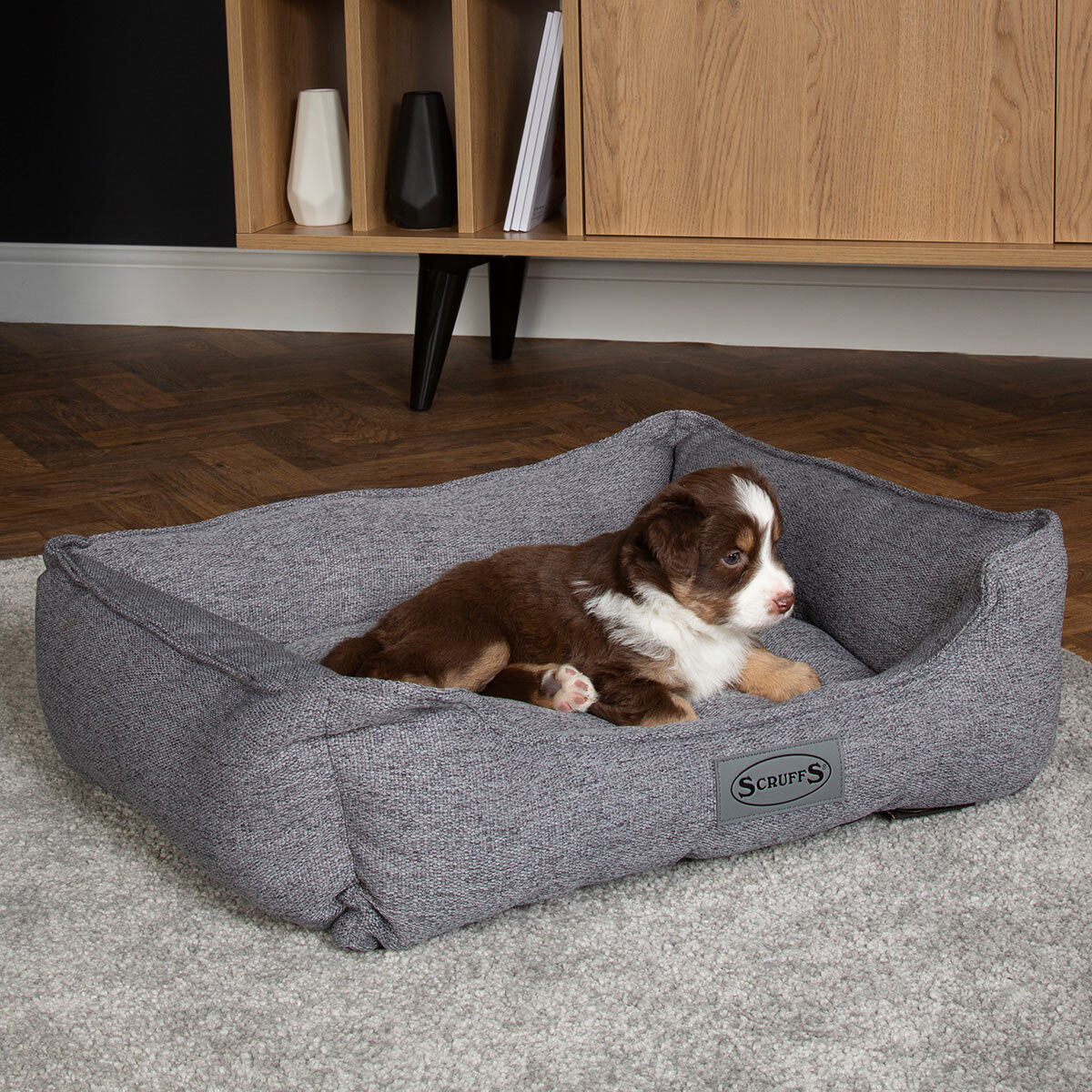 Lifestyle image of dog sitting on pet bed in living room setting