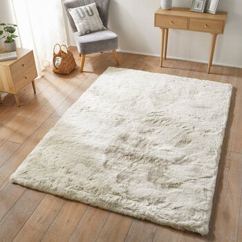 Cream-coloured fluffy textured rug on wooden floor Cream-coloured fluffy textured rug on wooden floor