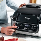 Lifestyle image of Ninja Foodi Grill with man using buttons